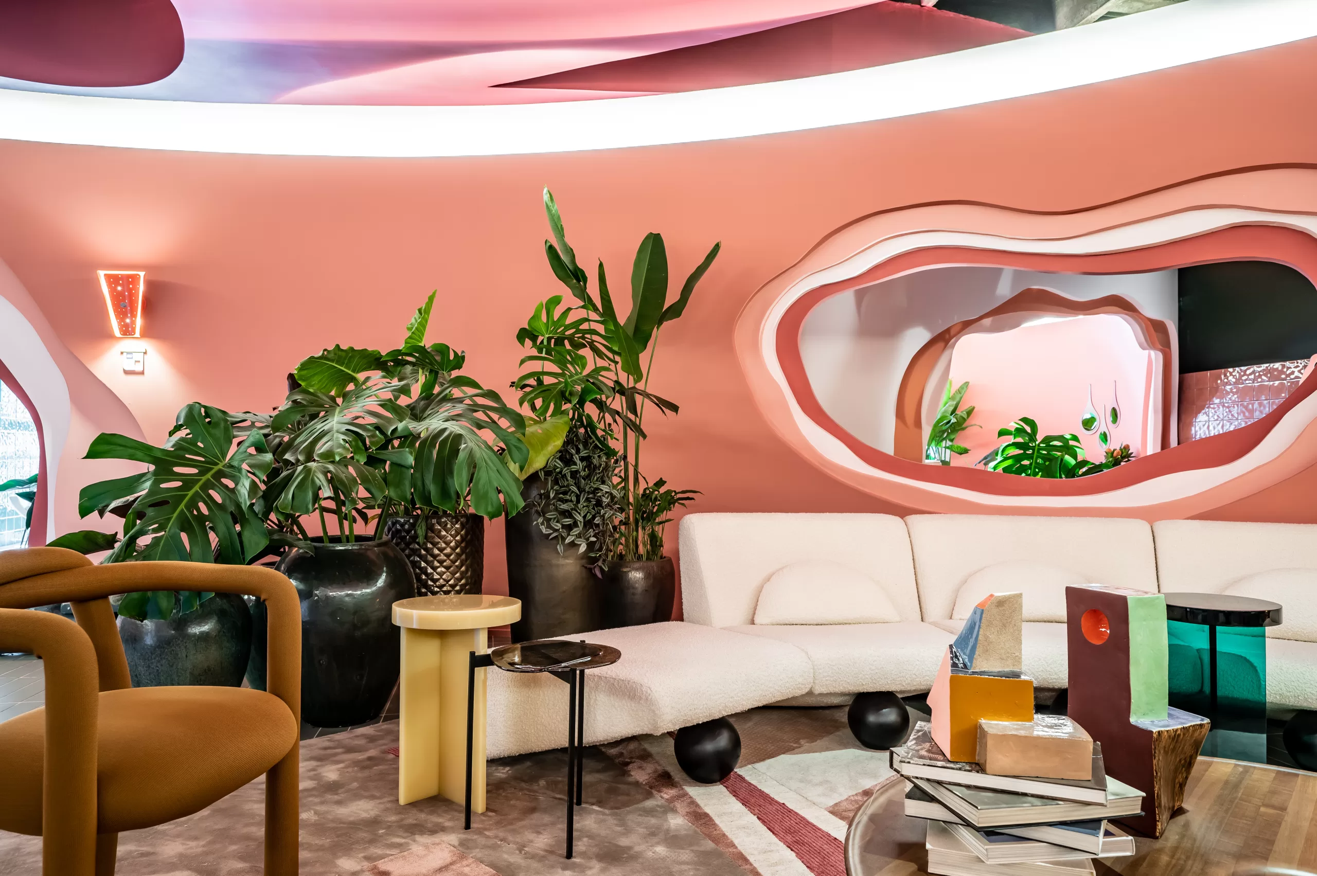 Sala com parede rosa e vários vasos grandes